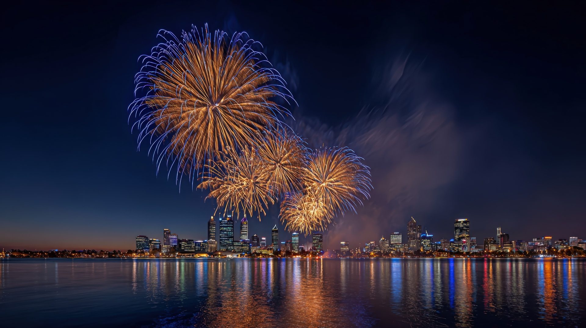 Fireworks over a harbour city skyline at night