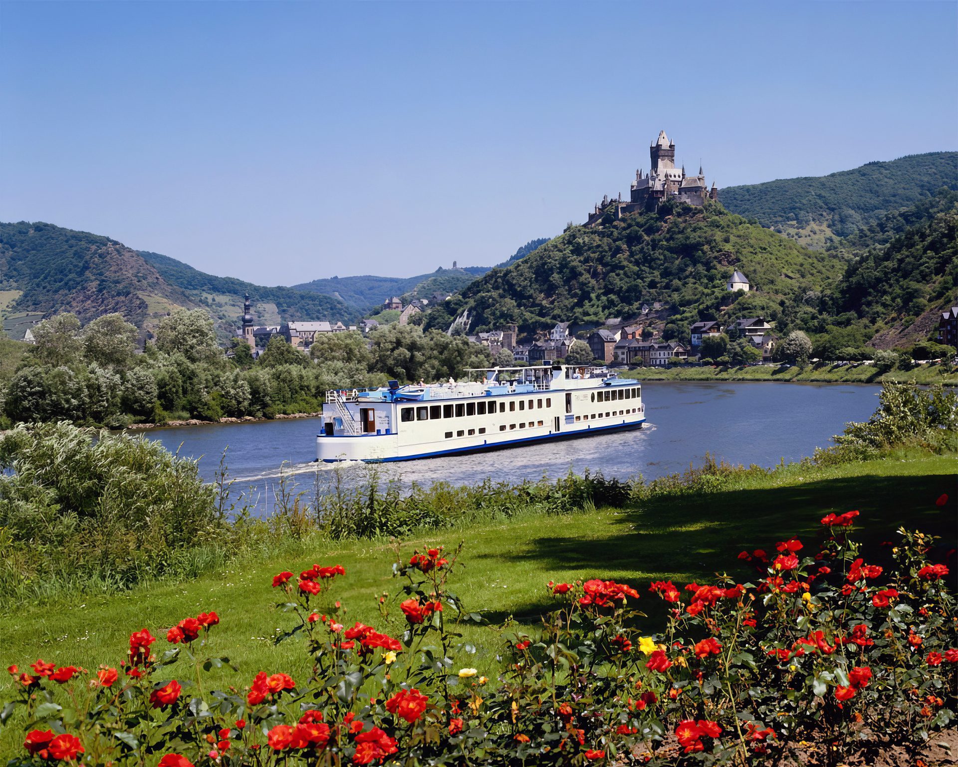 A river ship passing a hilltop castle above terraced vineyards