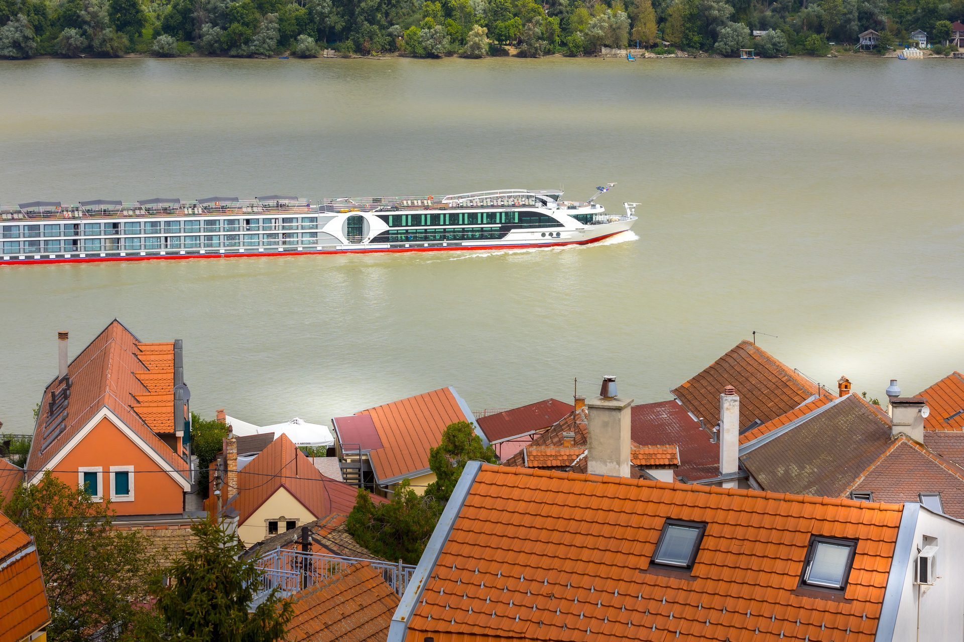 A river cruise ship on the Danube passing terracotta rooftops